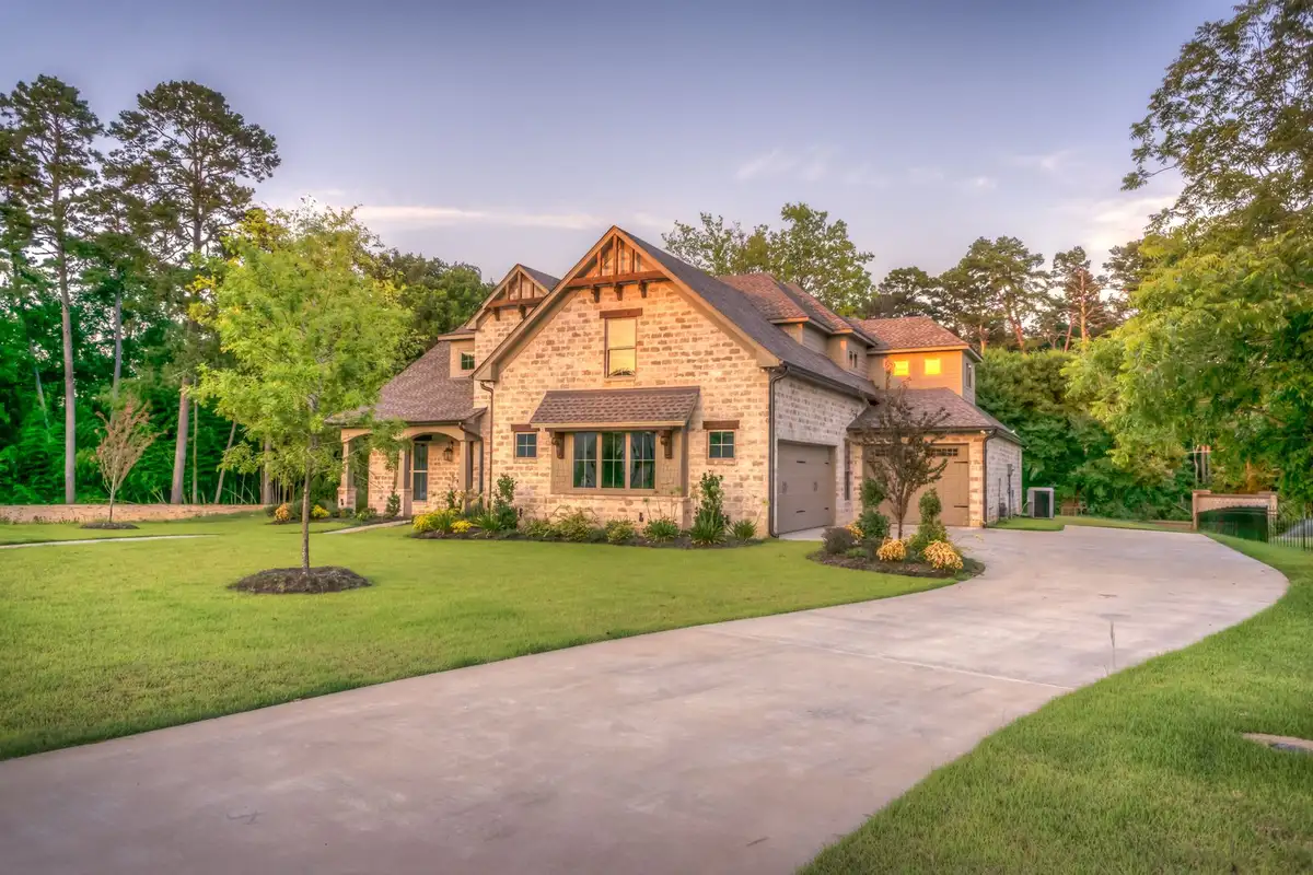 A stone house with an asphalt shingle roof and a curved driveway